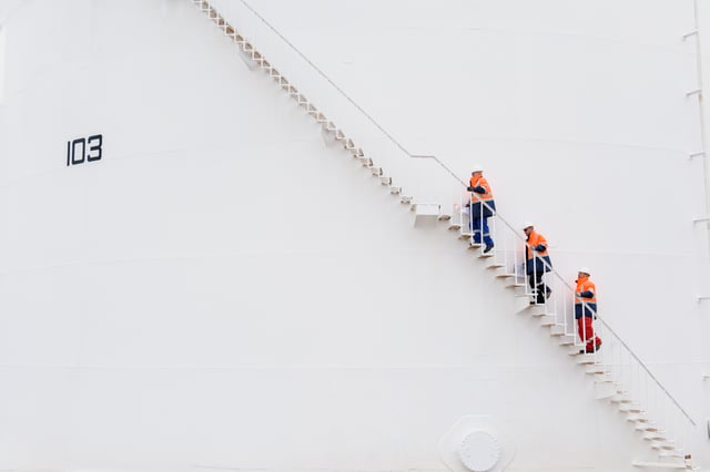People in construction gear climbing up a ladder